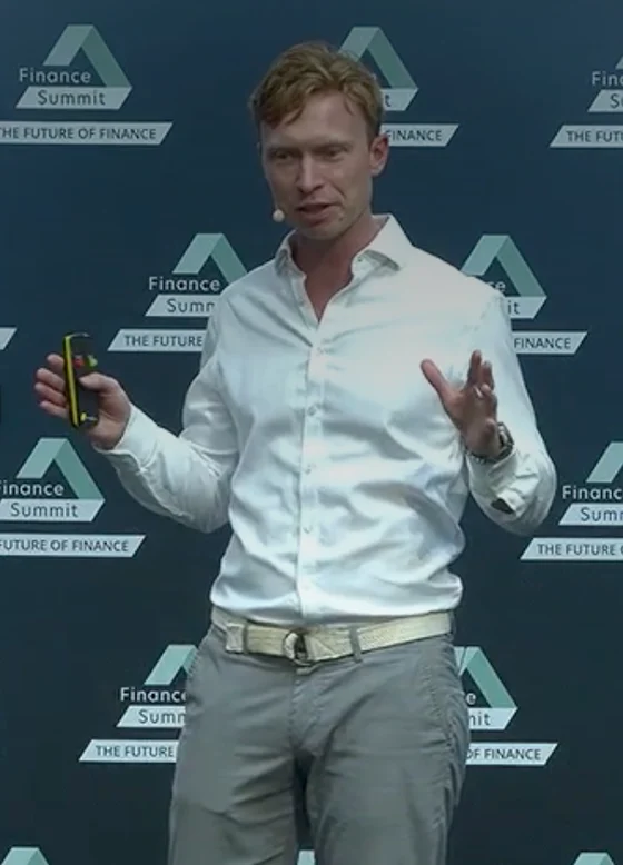 Themo Voswinckel presenting on the Finance Summit main stage, in front of the event backdrop